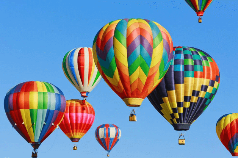 Imagen promocional del entrenamiento ‘Excelencia en Ventas’ mostrando varios globos de colores ascendiendo en el cielo azul, simbolizando el crecimiento en ventas.