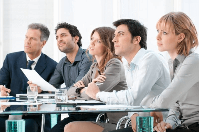 Imagen promocional del entrenamiento ‘Formador de Formadores’ mostrando a un grupo de personas escuchando atentamente a un instructor, simbolizando el éxito en la formación.